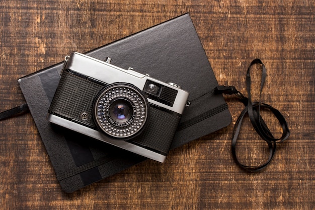 Free Photo an old-fashioned camera over the closed diary on wooden desk