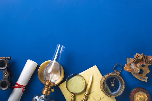 Old fashioned flat lay with retro travel, vacation accessories on blue wall.