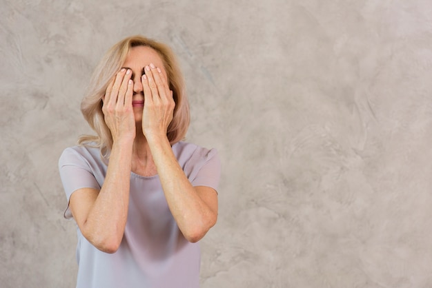 Old lady covering her face with copy space