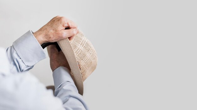 Old man holding hat and cane with copy space