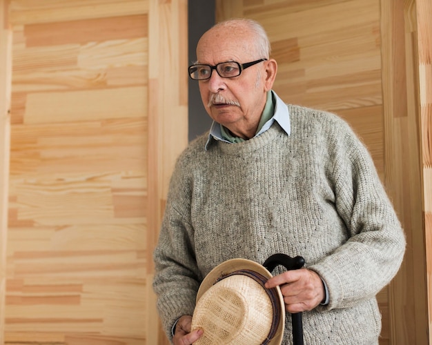 Free photo old man in a nursing home with cane and hat