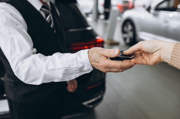 Old man receiving keys from car in a car showroom