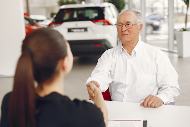 Free photo old man sitting in a car salon and talking with manager