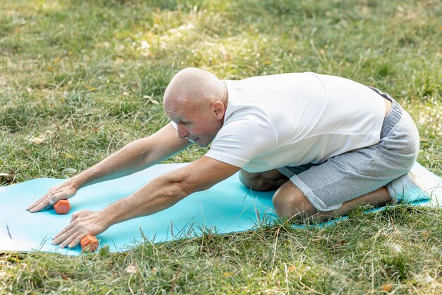 Old man stretching out on yoga mat