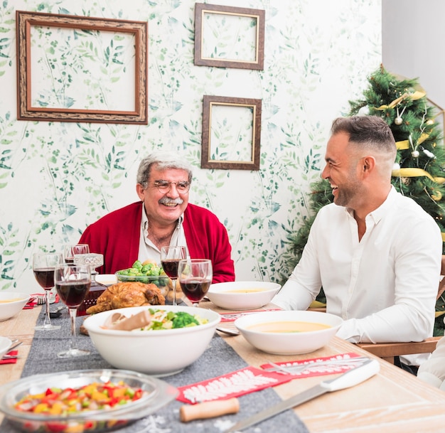 Old man talking to son at festive table