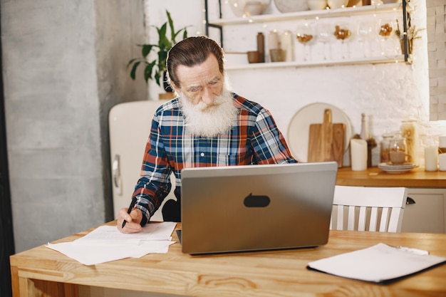 Free photo old man with laptop. grandfather sitting in a christmas decorations. man in a cell shirt.