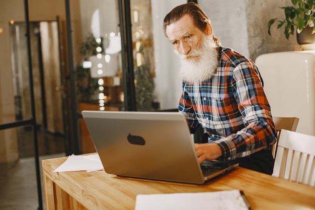 Free Photo old man with laptop. grandfather sitting in a christmas decorations. man in a cell shirt.