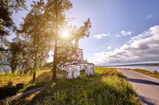 Old orthodox church at village. Summer view with floral meadow. Sunny day, blue sky with clouds.