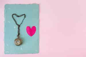 Free photo old pocket watch and little heart on blue paper