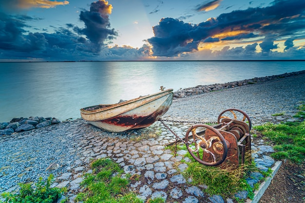 Free photo old rusty fishing boat on the slope along the shore of the lake