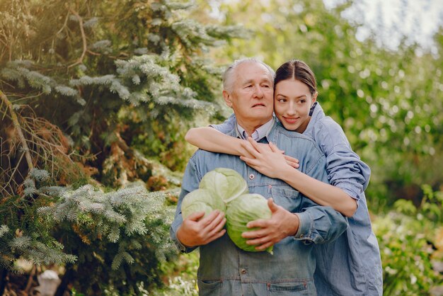 Old senior standing in a summer garden with cabbage