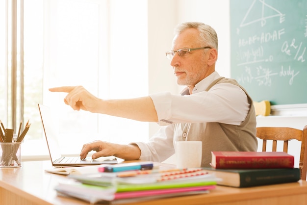 Old teacher pointing in classroom