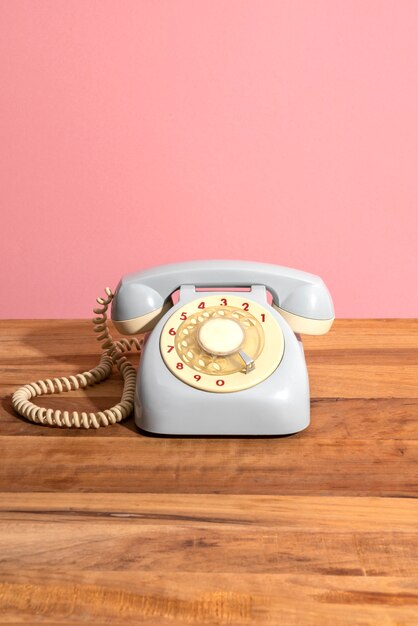 Old telephone on wooden table with pink wall