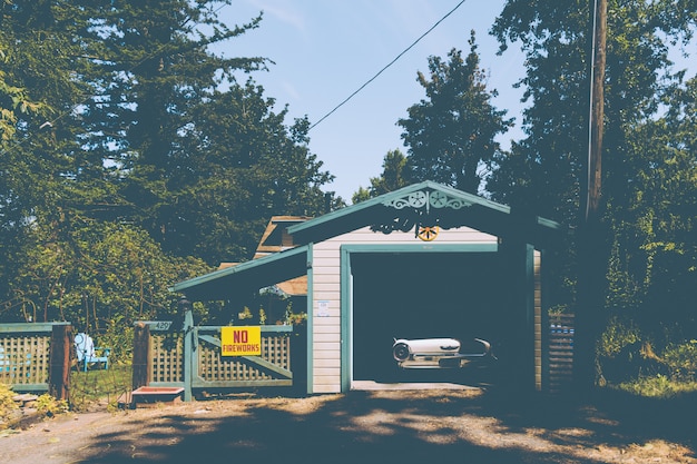 Free photo old vintage car parked in a small garage next to a sign on a fence