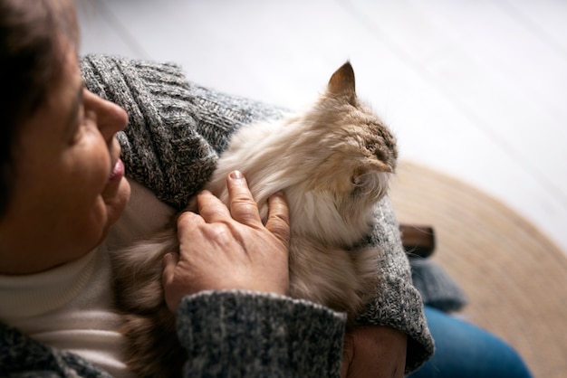 Free photo old woman petting cat high angle