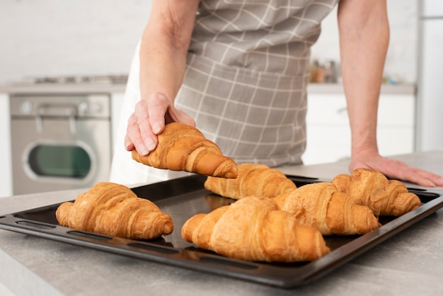 Old woman taking a croissant from the tray