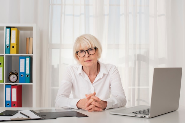 Old woman with eyeglasses sitting in her office