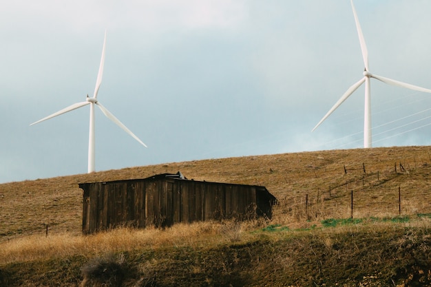 Free photo old wooden barn in a field with two windmills under the sunlight at daytime