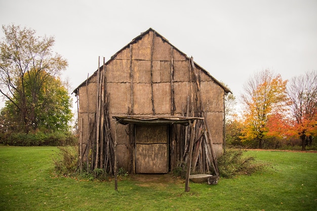 Free photo old wooden barn surrounded by trees in a field under a cloudy sky at daytime