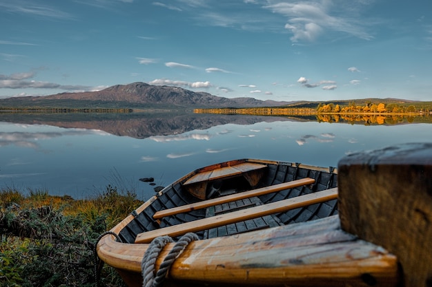 Old wooden boat on the shore of a lake during sunset