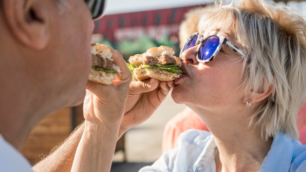 Free photo older couple enjoying eating a burger outdoors