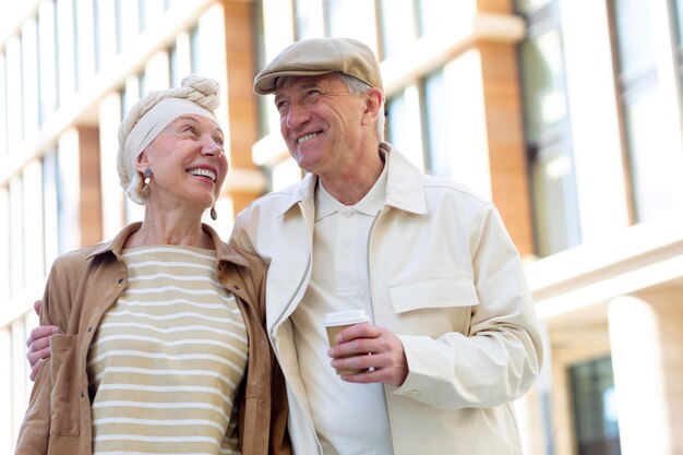 Older couple outdoors in the city with a cup of coffee