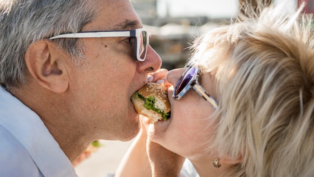 Older couple sharing a burger outdoors