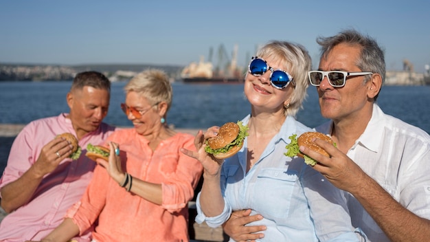 Older couples at the beach eating burgers together