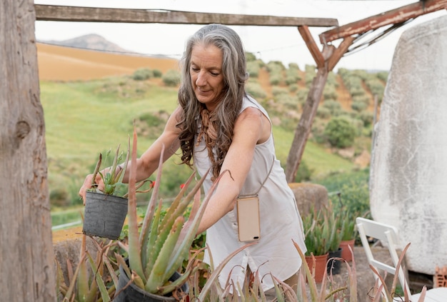 Free photo older female farmer watering her plants