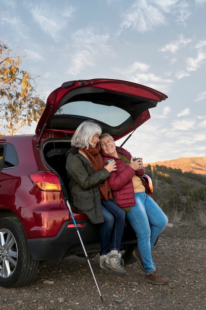 Free photo older female friends on an adventure from the trunk of their car