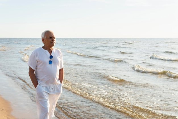 Older man enjoying the view while walking on the beach