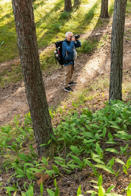 Free photo older man photographic nature while backpacking