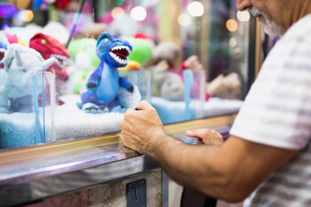 Older man playing toy claw machine