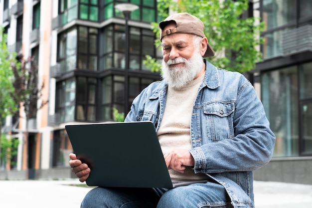 Older man using laptop outdoors in the city