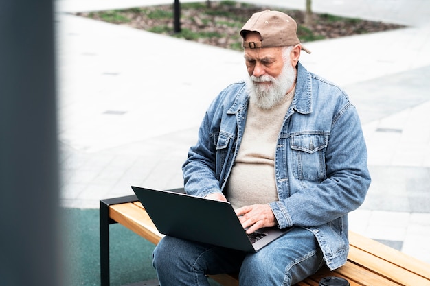 Older man using laptop outdoors in the city