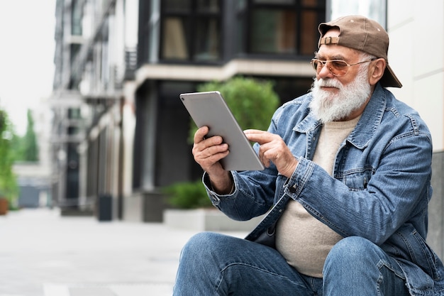 Older man using tablet outdoors in the city