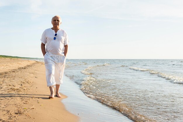 Older man walking by the beach enjoying the view