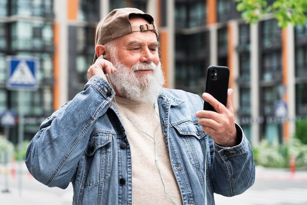 Older man with smartphone outdoors in the city