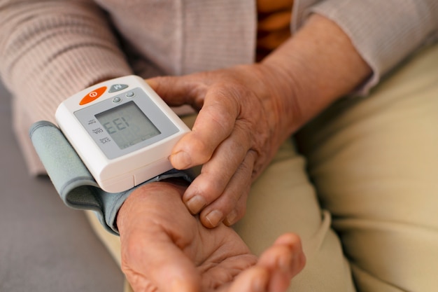 Free Photo older person checking their blood pressure with tensiometer