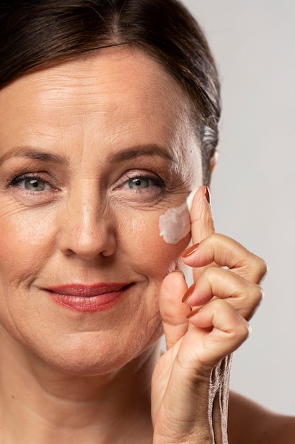 Free photo older woman using moisturizer on her face