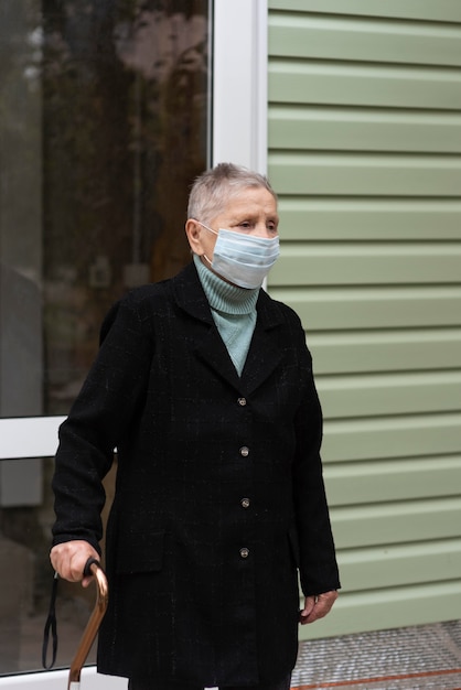 Older woman with medical mask carrying a cane