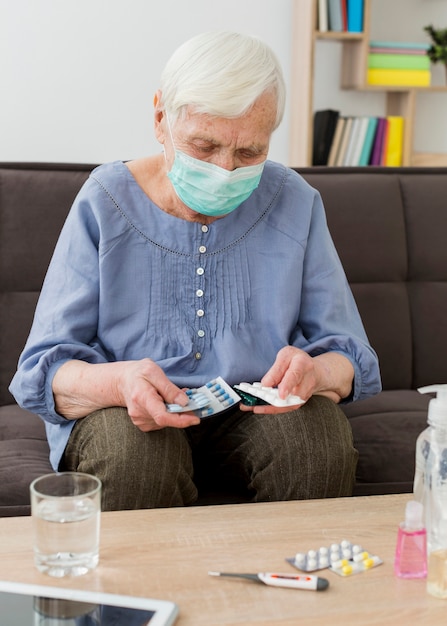 Free Photo older woman with medical mask taking her pills