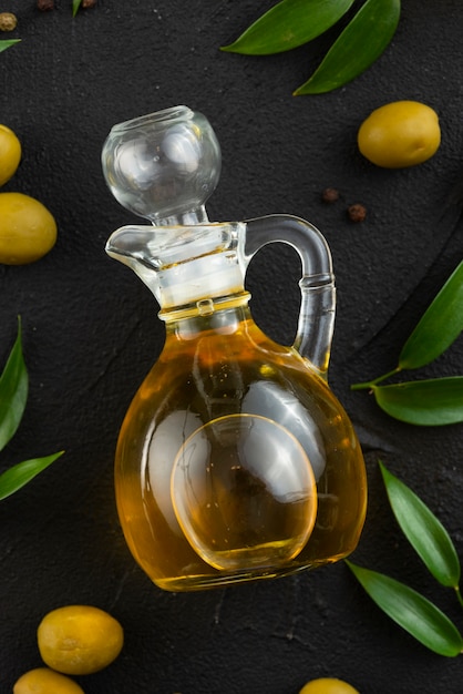 Free photo olive oil bottle on table with leaves and olives