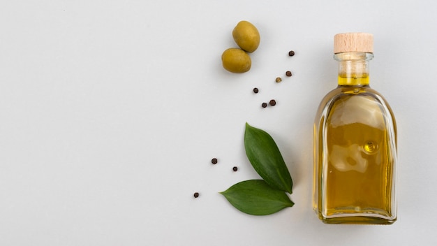 Free photo olive oil bottle with leaves and olives on table