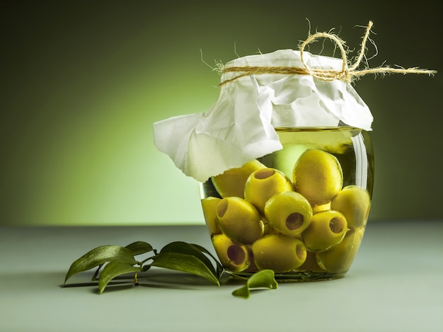 Free photo olive oil and olive branch on wooden table