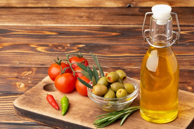 Free photo olive oil olives and tomatoes on wooden background