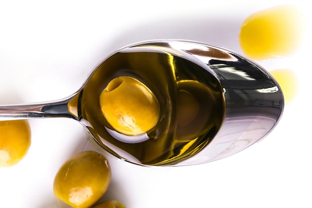 Olive oil in spoon and olive