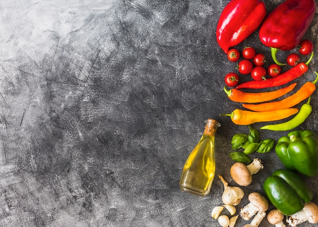 Free Photo olive oil with colorful vegetables on grunge textured background