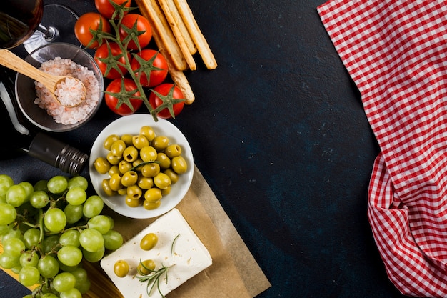 Olives, tomatoes and grapes on dark surface