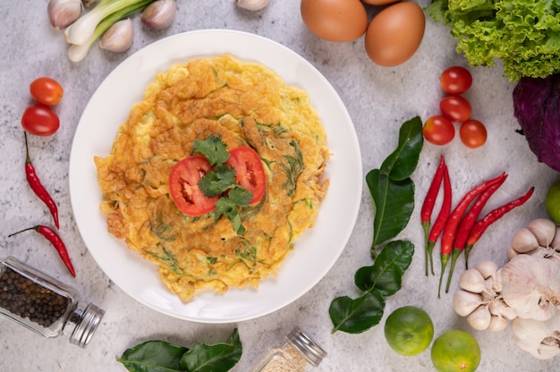 Free photo omelet in a white plate garnished with tomatoes and coriander.